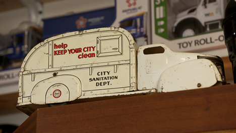 A diecast toy replica of a white garbarage truck.