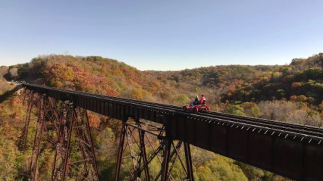 People riding a bike on a railway bridge.