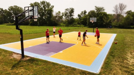 Five people playing basketball on a purple and yellow court