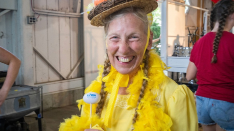 Women's chicken calling participant dressed in a yellow, feathery dress with an egg hat