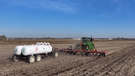 anhydrous tanks being pulled by a tractor with a blue sky in the background