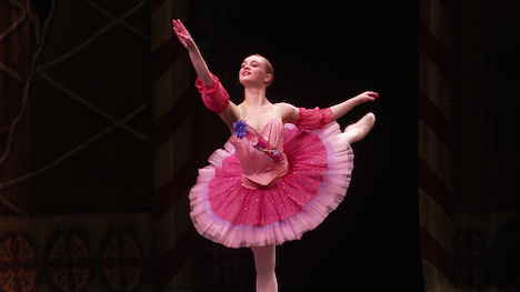 Ballet dancer in pink costume with arm and leg extended