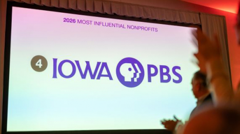A large screen at an event with the Iowa PBS logo on the screen