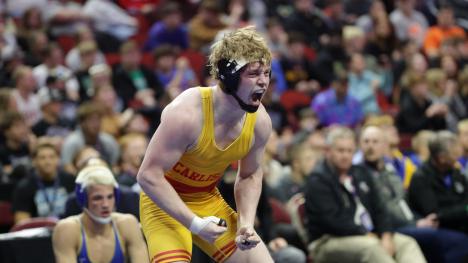 High school male wrestler celebrating win with mouth open and arms in fists