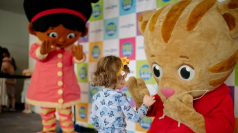 Miss Elaina and Daniel Tiger mascot costumes from Daniel Tiger's Neighborhood giving a high five to a small child.