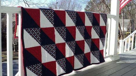A quilt hanging over a porch railing.