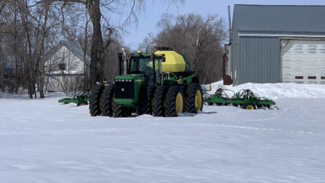 Green tractor in snow.
