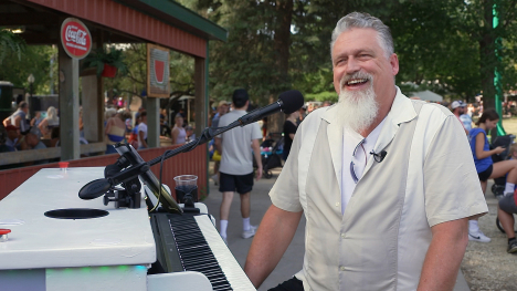 Piano player, Jim Ripp sits smiling at his strolling piano.