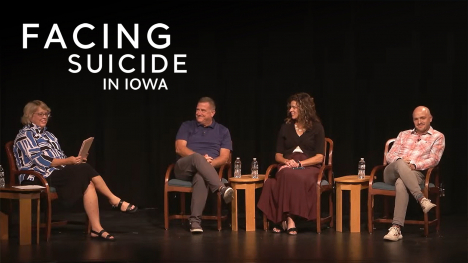 A host and three guest participants sitting in chairs on stage during a live Facing Suicide in Iowa event.