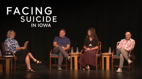 A host and three guest participants sitting in chairs on stage during a live Facing Suicide in Iowa event.