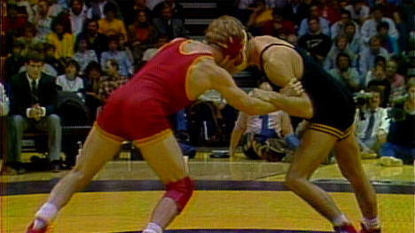 An Iowa State University wrestler engages his opponent from the University of Iowa during a match.