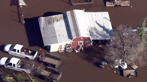 A flooded property with a building and vehicles.