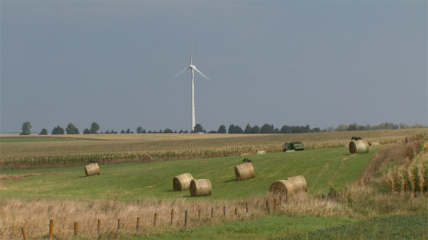 A field with bales of hay...a wind turbine in the distance.