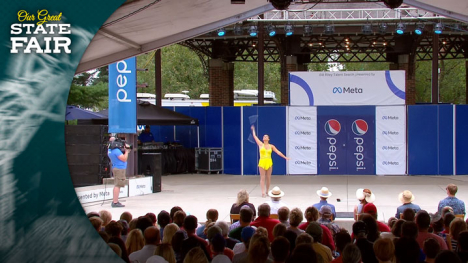 Girl in a yellow costume tosses a baton in the air