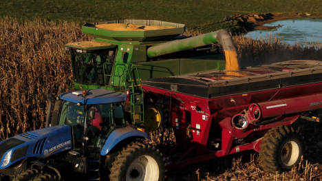 A tractor and combine harvesting corn in a field.
