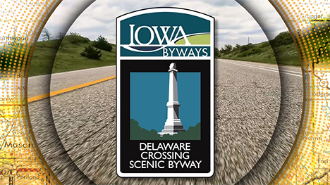 Iowa Byways: Delaware Crossing Scenic Byway sign overlayed on a road background.