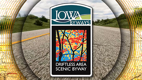 Iowa Byways: Driftless Area Scenic Byway sign overlayed on a road background.