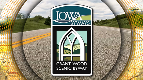 Iowa Byways: Grant Wood Scenic Byway sign overlayed on a road background.