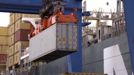 A shipping container gets moved on/off a ship.