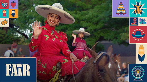 Two women on horseback riding in the Iowa State Fair parade and waving to the parade crowd.