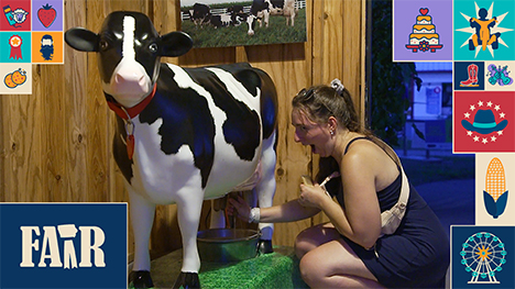 A woman milks a cow statue.