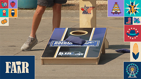 Two beanbags at rest on a cornhole hole board, next to a participants legs.