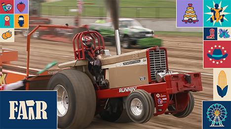 A smoke billowing muscle tractor pops-a-wheelie while competing in the tractor pull competition.