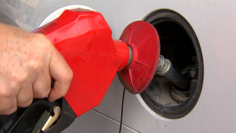 A hand holds a red gas pump in a car gas tank.