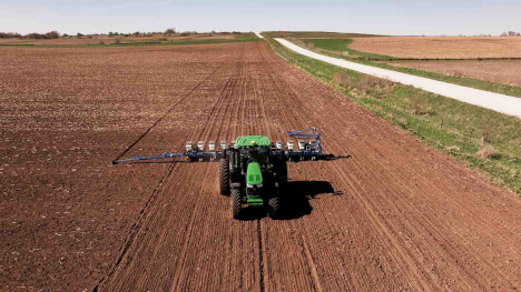 Green tractor planting in Iowa field.