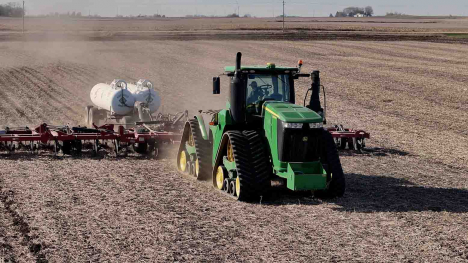 John Deere green tractor applying anhydrous ammonia fertilizer to a farm field