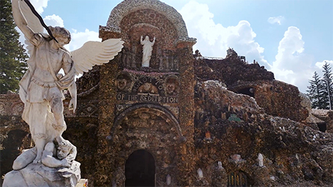 A white statue of an angel stands near the Grotto of the Redemption.