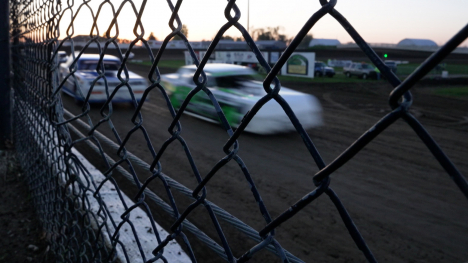 Marshalltown Speedway - race cars race on a dirt track behind a fence.