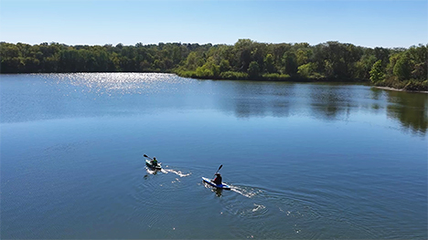 Two people enjoy the waters of George Wyth State Park in their canoes.