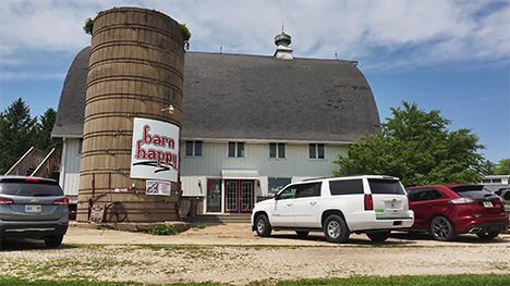 An exterior view of Barn Happy -- a converted silo and barn. Vehicles are parked out front.