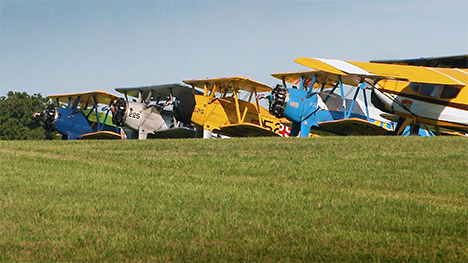 Antique airplanes lined up on a grassy field.