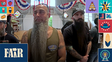 Several bearded men line up near the stage of Pioneer Hall to be judged in the 2026 Beard Growing Contest.