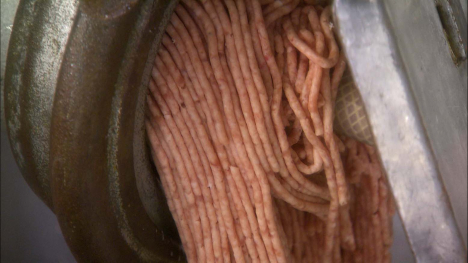 ground beef emerging from a commercial grinder
