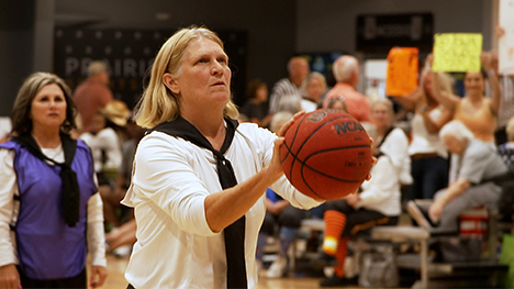 A member of the Granny Basketball League holds a basketball to set up a shot on basket.